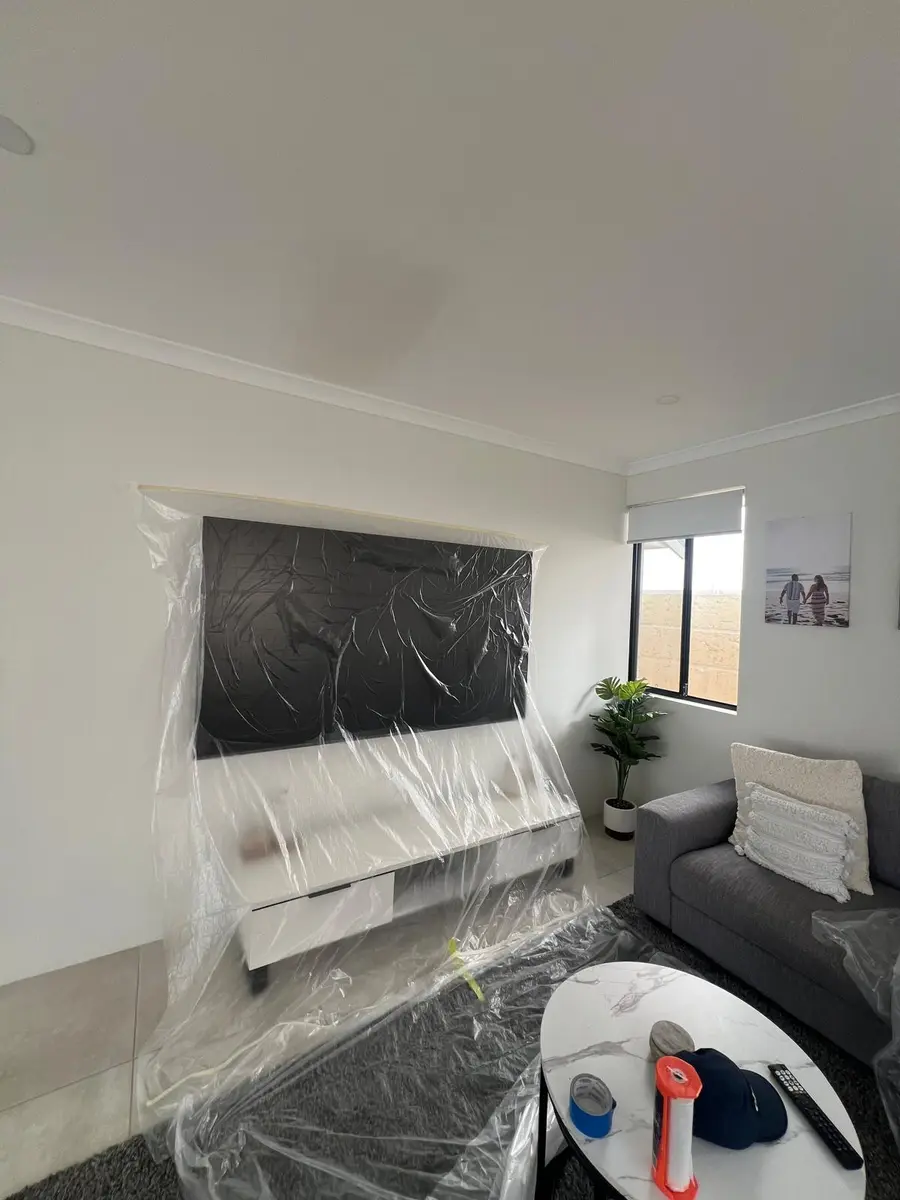 Lounge room furniture and TV wrapped in plastic before painting