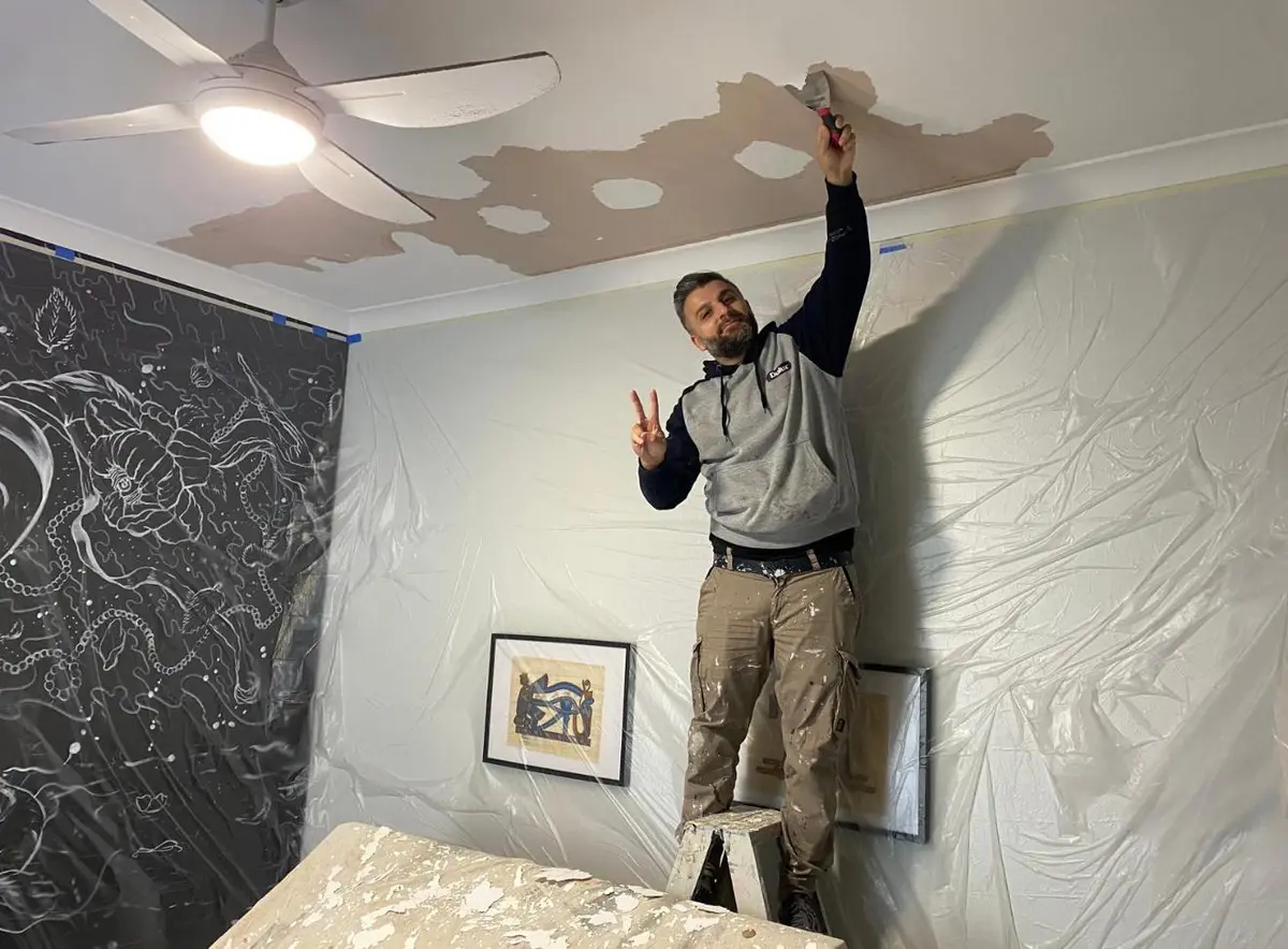 Kevin patching and repairing a damaged ceiling before painting