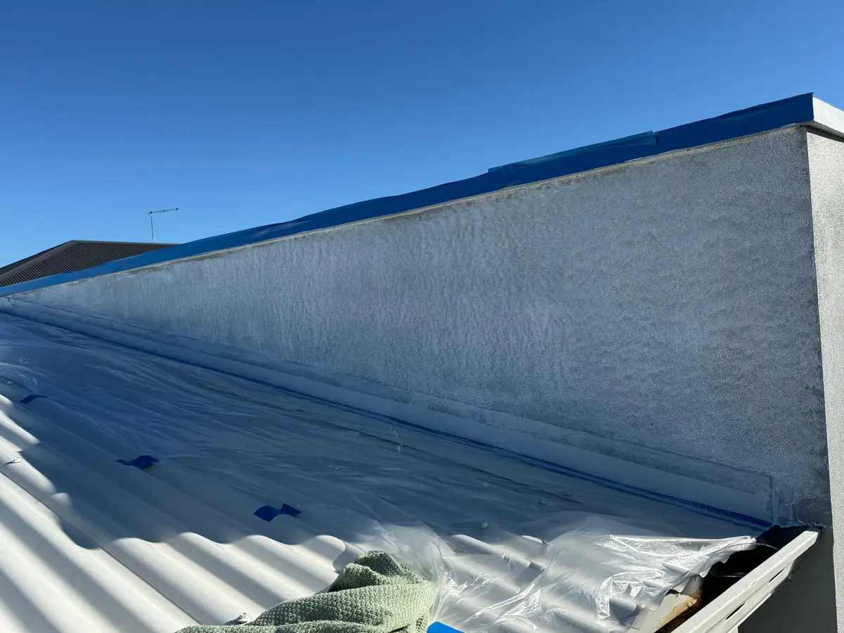 Painting a parapet wall at roof level with the metal roof sheets masked off